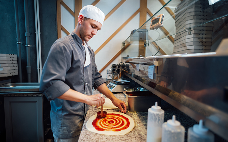 cook spreads tomato sauce on pizza dough caterin 2023 11 27 04 50 24 utc